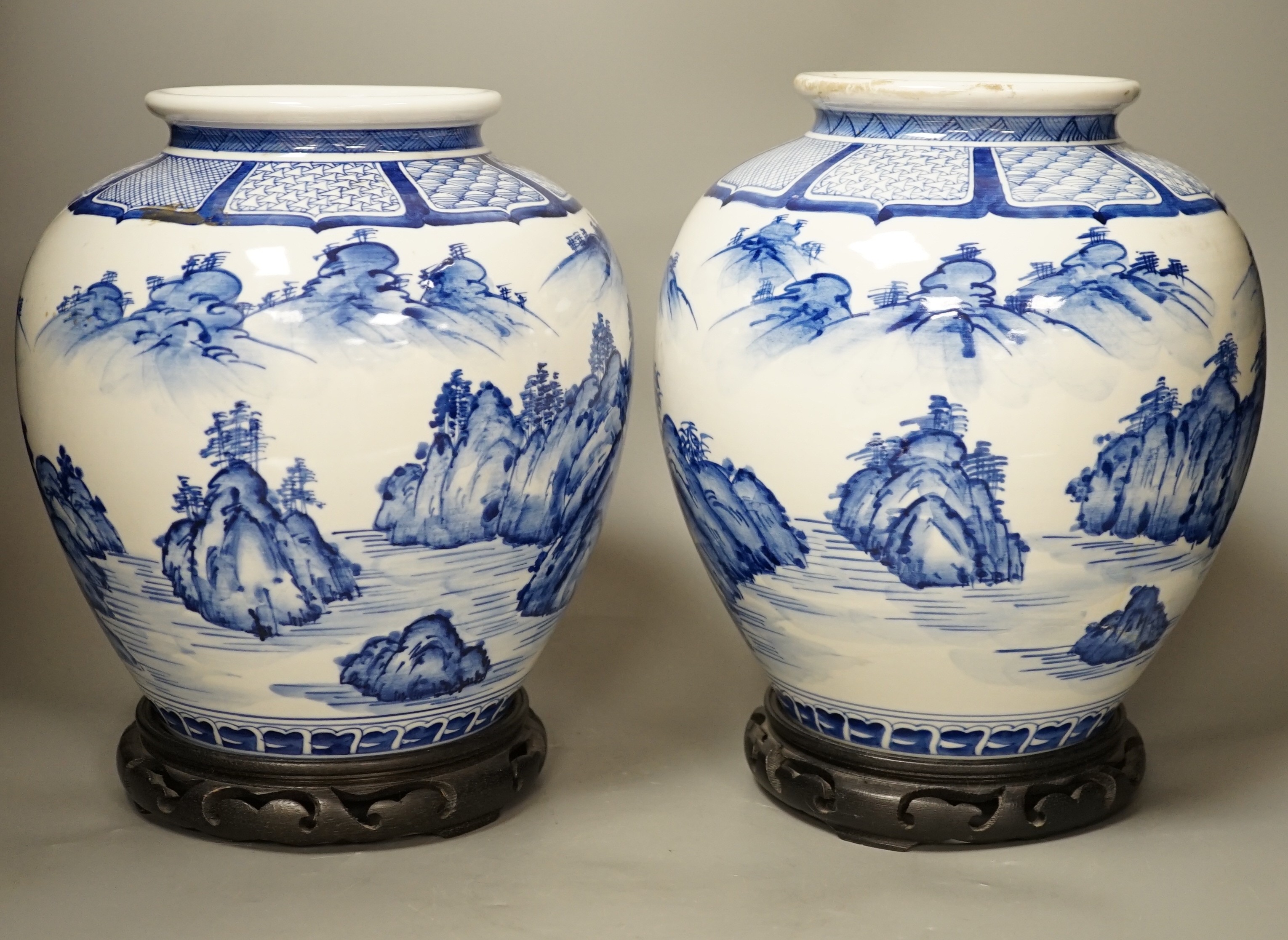 A pair of large Japanese blue and white vases, on wood stands, 26cms high of including stand.